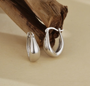 Detailed view of S925 sterling silver stamp on minimalist polished U-shaped earrings