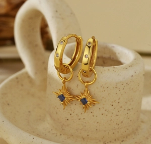 Dettaglio di orecchini a cerchio vintage in oro con ciondoli a stella in zaffiro