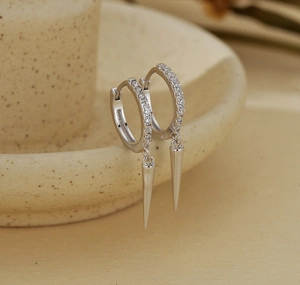Macro shot of silver S925 earrings with sparkling zircon hoops and sleek cone pendants