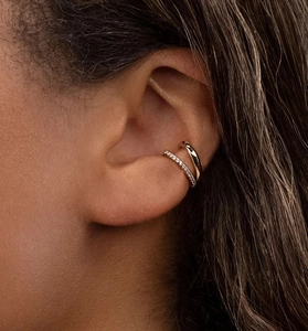 Gros plan d'un ear cuff double couche doré avec cristaux pavés sur une oreille
