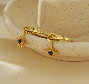 Dettaglio degli orecchini a stella dorati con zaffiro blu su una ciotola di ceramica