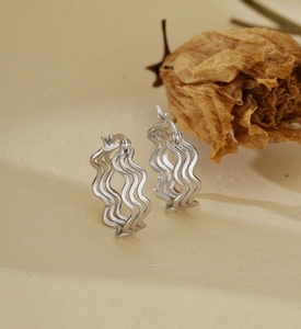 Détail macro de créoles en argent sterling S925 avec design de texture ondulée multicouche