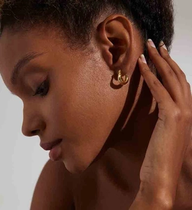 Close-up of polished gold U-shaped hoop earrings worn by a model for a minimalist look