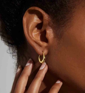 Close-up of polished gold U-shaped hoop earrings worn by a model for a modern look