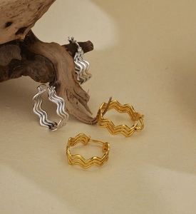 Détail macro de boucles d'oreilles créoles vagues en argent fin S925 or et argent