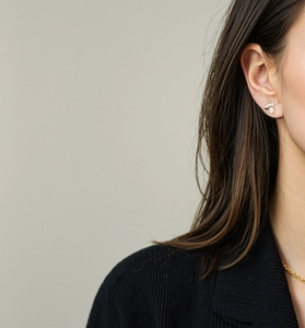 Détail de boucle d'oreille argentée en V avec zircon sur mannequin portant un tricot noir