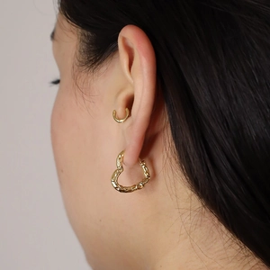 Élégantes boucles d'oreilles cœur en argent 925 doré avec texture irrégulière sur modèle