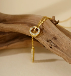 Detail of adjustable golden Y-necklace with shimmering pavé circles on rustic wood