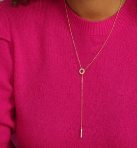 Detail of a golden adjustable lariat necklace with micro-pave crystals on a pink sweater