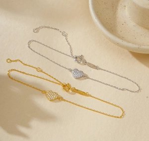 Macro shot of S925 sterling silver bracelets with pavé heart charms in gold and silver
