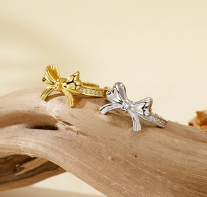Détail de bagues nœud en argent S925 avec zircons brillants sur support en bois