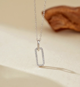 Macro shot of silver rectangle pendant with micro-pave crystals on thin chain