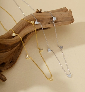 Gros plan de colliers S925 or et argent avec cœurs en zircon sur décor en bois
