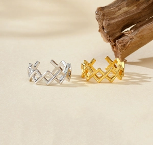 Detail view of gold and silver S925 sterling silver lattice rings on a textured surface