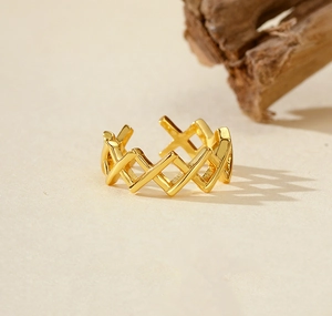 Close-up of golden geometric woven cross ring with adjustable open band and polished finish