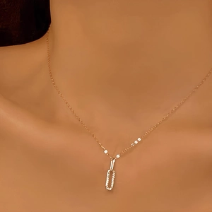 Close-up of golden interlocking rectangle pendant necklace on a minimalist chain