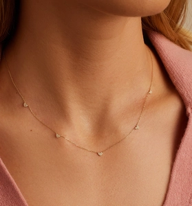 Modèle portant un collier doré avec cinq breloques en cœur pavées de pierres zircon