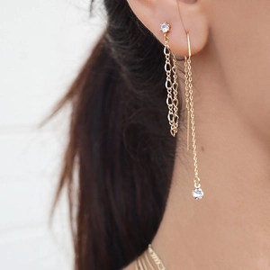 Élégantes boucles d'oreilles dorées en U avec pompons et cristaux brillants sur modèle
