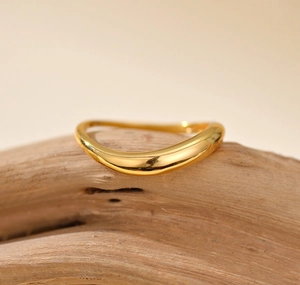 Makroansicht eines polierten goldenen Wellenrings auf Holz mit warmen Lichtakzenten