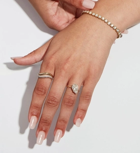 Nahaufnahme von Birnenschliff-Diamantring, Stapelring und Gold-Tennisarmband an Hand