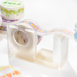 Minimalist frosted acrylic tape dispenser with decorative floral and bow washi tapes