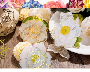 Detail shot of vintage 3D flower stickers with gold foil edges on a wooden table