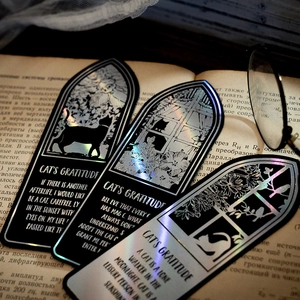 Black cat bookmarks with holographic laser print on vintage book with glasses