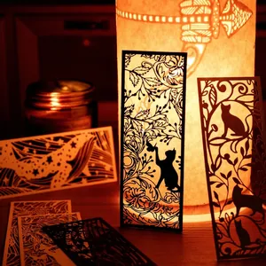Exquisite laser-cut paper bookmarks featuring cat and whale silhouettes in warm light
