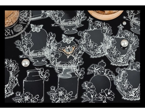 Macro shot of white floral and perfume bottle PET stickers on elegant black background