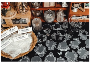 Macro shot of white vintage PET stickers with birdcages and clocks on black surface