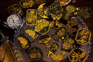 Detalle de pegatinas vintage en negro y oro con motivos florales y de mariposas