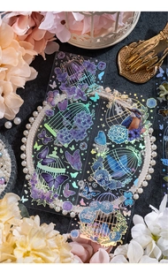 Macro detail of PET stickers with iridescent laser birdcage and butterfly motifs