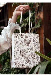 Detail of vintage flower and bird printed paper gift bag with white woven handles