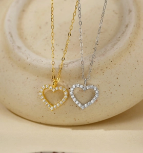 Macro detail of 925 sterling silver hollow heart pendants with zircon pave in gold and silver