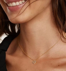 Close-up of hollow heart pendant necklace with white stones worn by a model