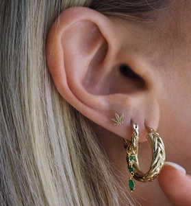 Gros plan de boucles d'oreilles créoles torsadées dorées avec des zircons verts