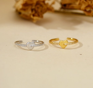 Detail of gold and silver S925 heart rings with sparkling cubic zirconia on an open band