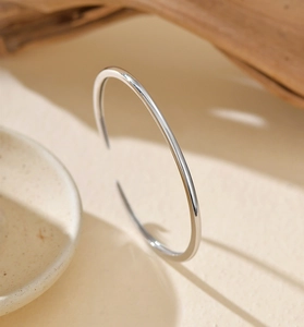 Polished S925 sterling silver open bangle with sleek finish on natural background