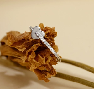 Macro shot of silver heart ring with sparkling pave diamonds on dried petals
