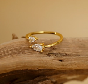 Macro detail of gold adjustable ring with two pear-cut cubic zirconia on wood