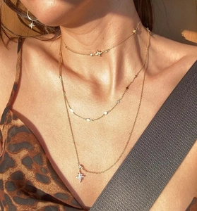 Détail de colliers superposés dorés avec pendentifs étoiles et détails pailletés
