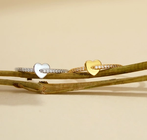 Detail of silver and gold heart rings with pave zircons on minimalist wood branches
