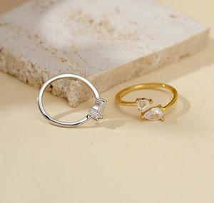 Detailed view of gold and silver open rings with pear-cut cubic zirconia settings