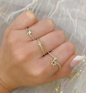 Detail of three stacked gold-plated silver rings with heart and star micro-pave crystals
