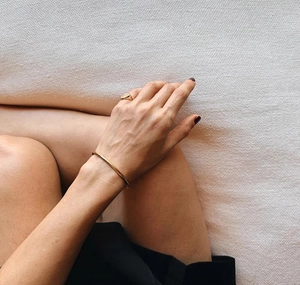 Detail of minimalist gold plated S925 sterling silver open cuff bracelet and signet ring