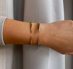 Detail of minimalist open cuff bracelets in gold and silver finish with teardrop tips