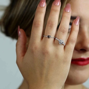 Detailed view of layered S925 silver heart rings with pavé diamonds on finger