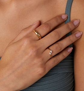 Detailed close-up of gold pear-cut zircon open ring and thick rounded band on finger