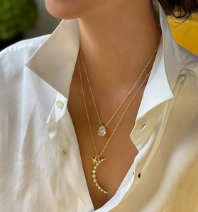 Détail du collier à deux rangs doré avec pendentifs lune en opale, étoile et goutte