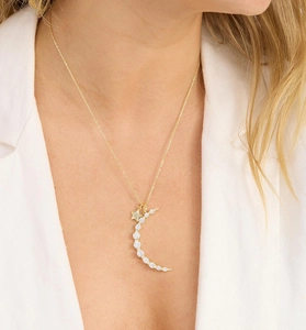 Détail du pendentif lune et étoile dorées avec pierres brillantes porté au cou